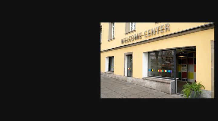 Eingang des Welcome Centers Stuttgart mit Schaufenster und Beschilderung.