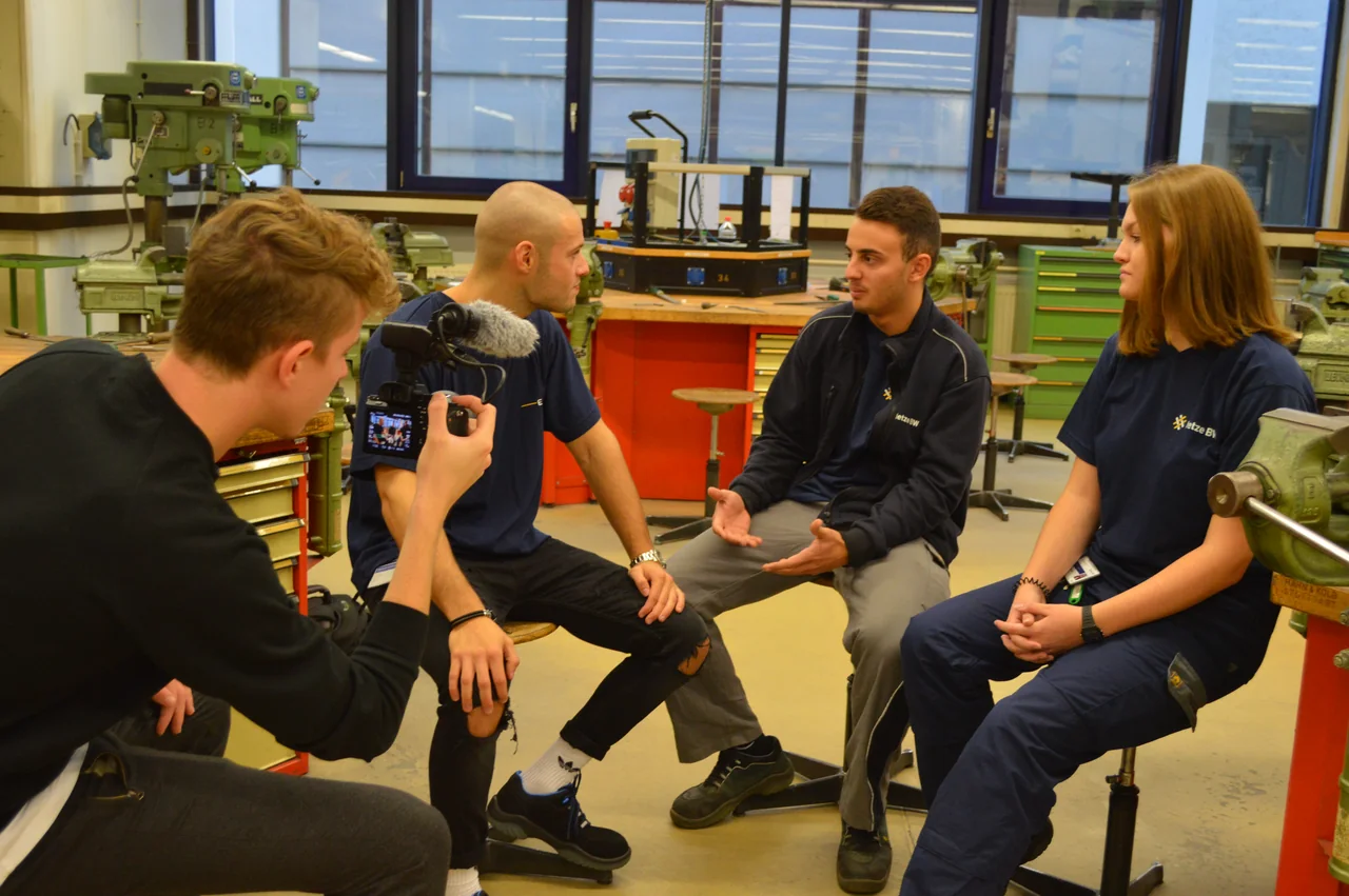 Creator und Auszubildende sitzen im Gespräch in einer EnBW-Werkstatt.