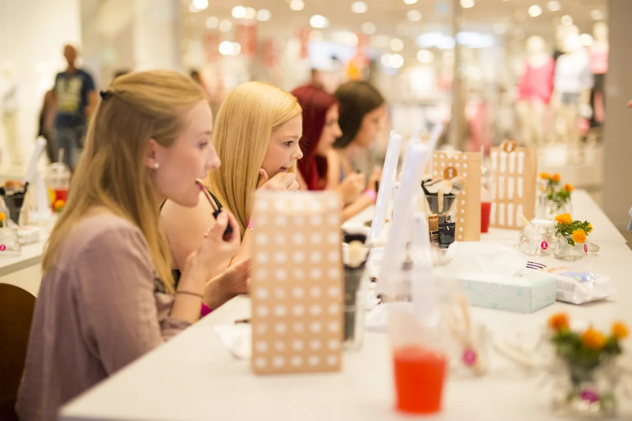 Besucherinnen probieren Make-up an Spiegeln während der GERBER Beauty Days.