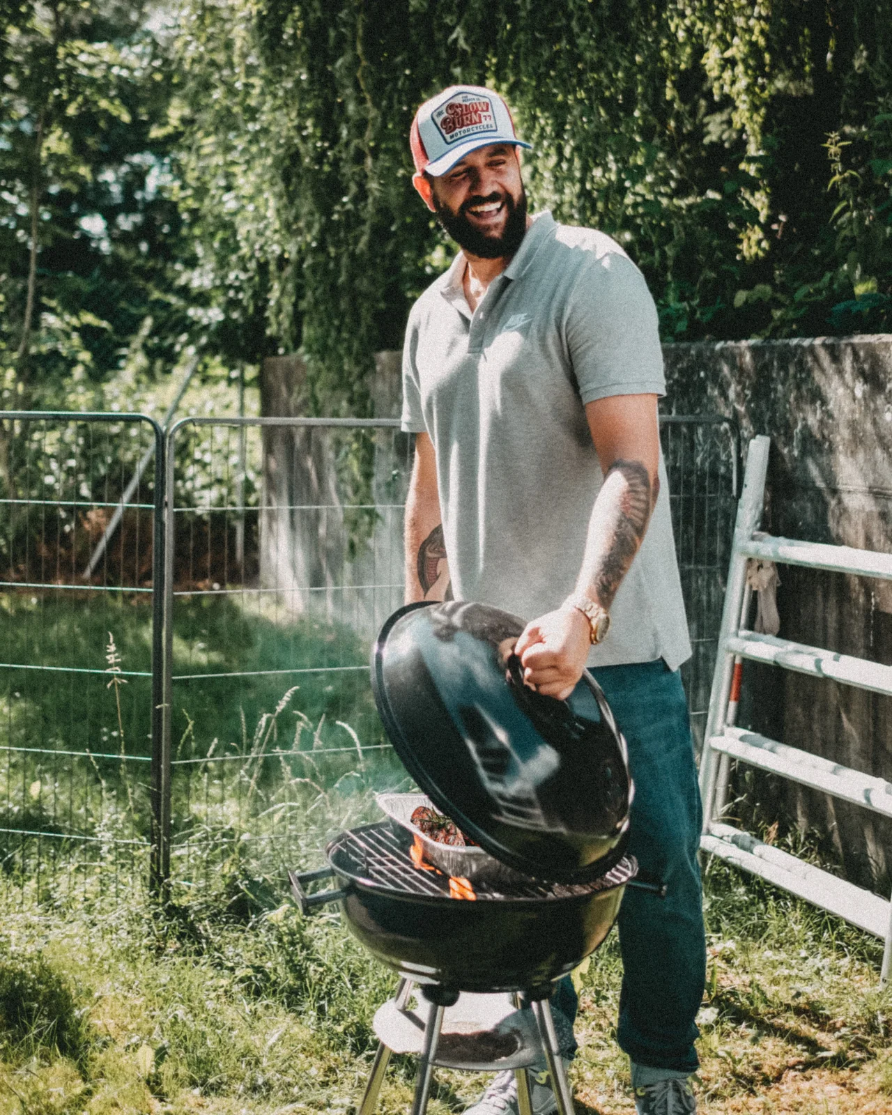 Creator Ben Kauer steht mit Grillutensilien im Garten.