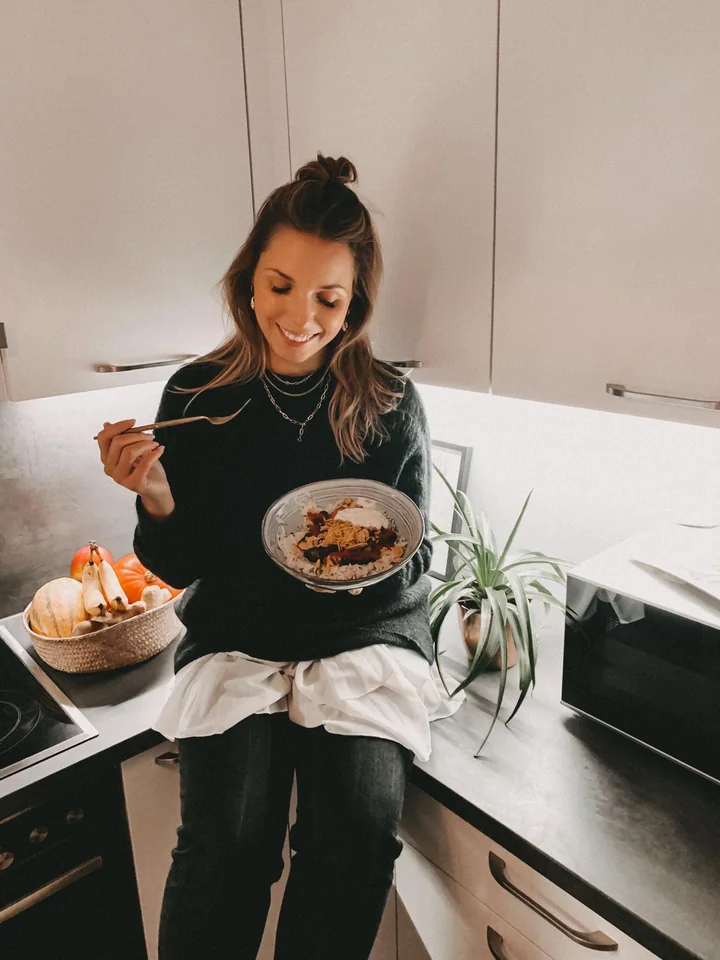 HelloFresh-Creatorin hält ein selbst zubereitetes Gericht in ihrer Küche.