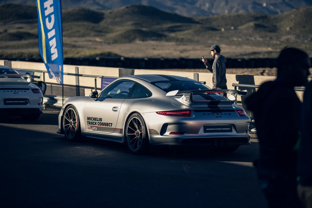 Teilnehmer steht neben einem weißen Sportwagen beim MICHELIN-Track-Connect-Erlebnis.