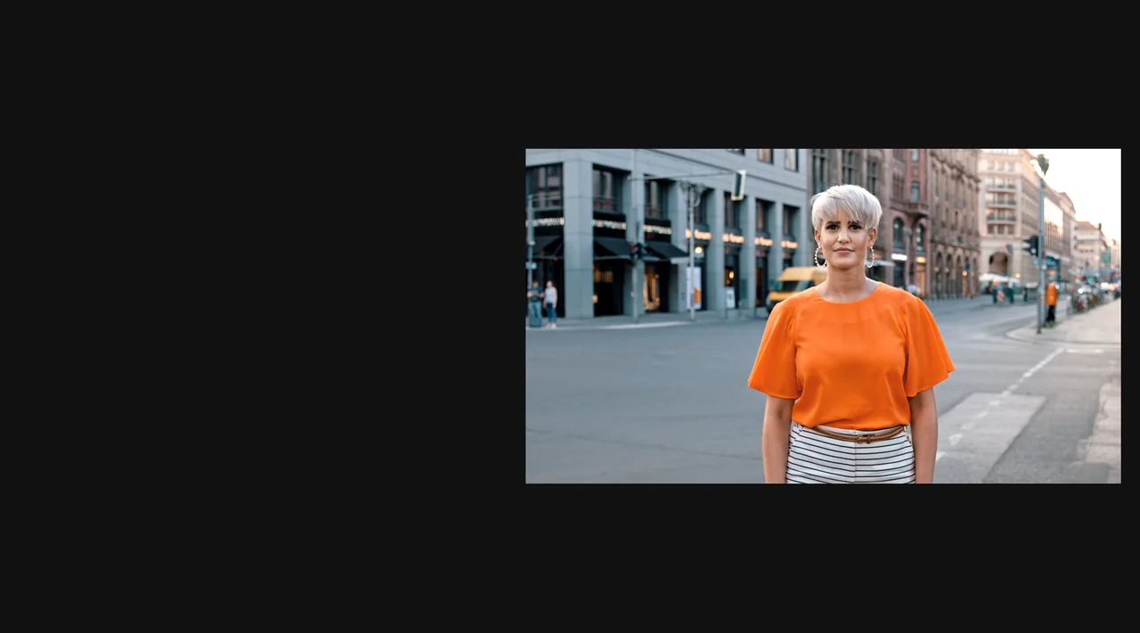 Creatorin Madeleine Schön im orangefarbenen Oberteil auf einer Berliner Straße.
