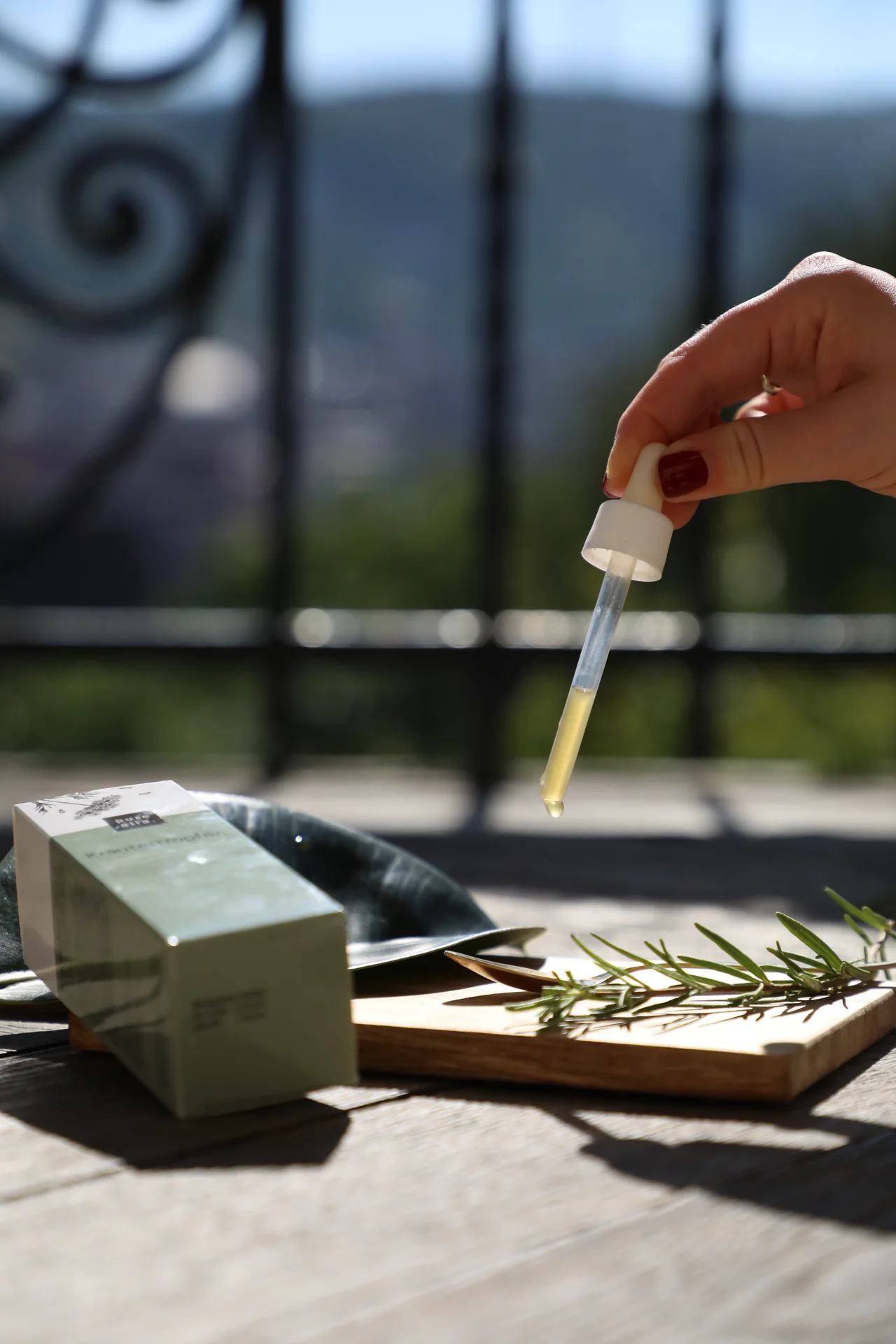 Kräutertropfen werden am Fenster mit einer Pipette entnommen.