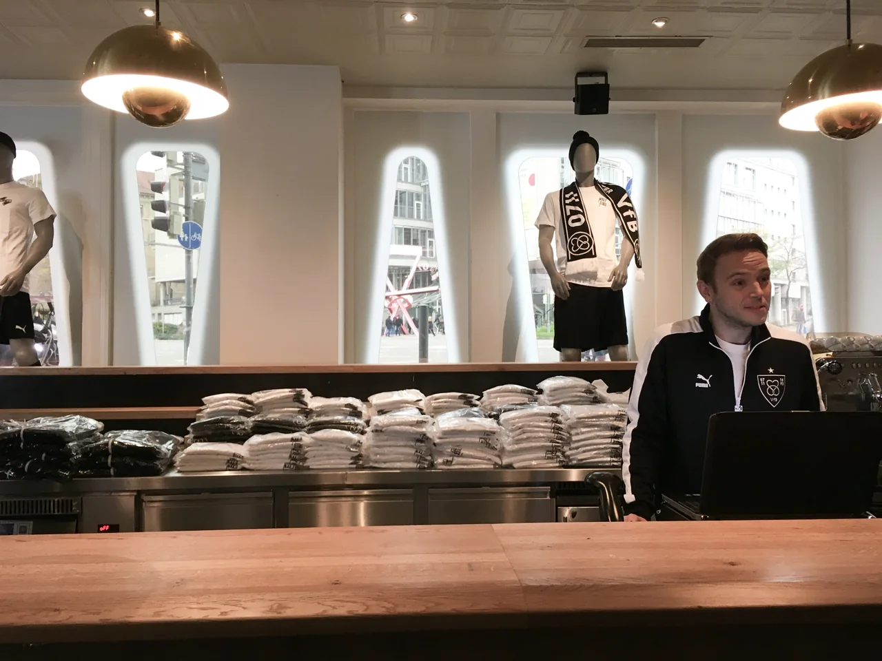 VfB-Fan im Store zwischen Fanschal und Trikot der #WIRSINDSTUTTGARTER-Kampagne.